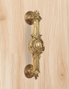 Ornate brass door handle, golden finish, close-up on round backplate