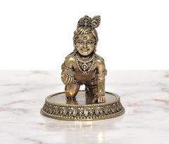 Bal Krishna laddu Gopal brass idol, front view; detailed jewelry and kneeling posture