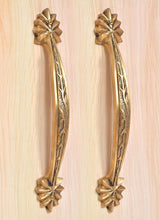 Set of two golden brass handles featuring leaf-carved stems and starburst rosette end caps.