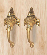 Brass Ganesha face door handles pair, close-up of faceplate and golden lever grips