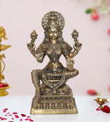 Lakshmi goddess statue, four-armed seated pose, ornate crown and jewelry, brass tone
