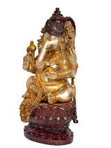 Side view of seated Ganesha idol with gold-toned trunk and dark red lotus base