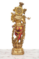 Rückansicht Krishna-Statue: goldfarbene Ornamente, rotes Gewand, Flöte seitlich
