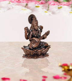 Copper Maa Saraswati idol, seated side view with veena and raised hands, lotus base