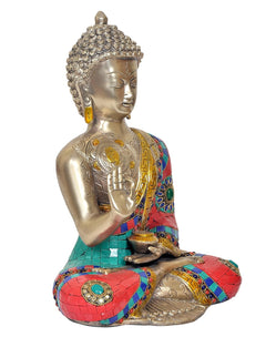 Brass Buddha statue three-quarter view, seated pose with colorful robe panels