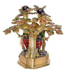 Back view of brass Radha Krishna flute idol beneath ornate tree branches
