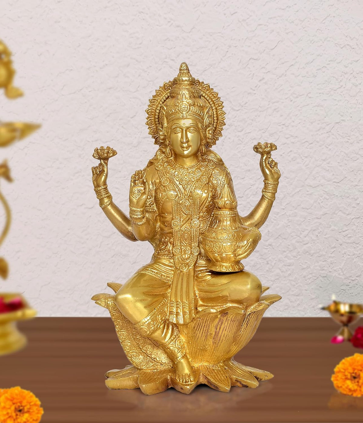 Brass Lakshmi idol seated on lotus with four arms raised, ornate detailing