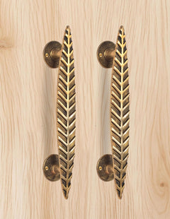 AONA brass leaf door handle pair, golden, two vertical bars on light wood