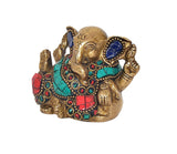 Brass Lord Ganesha figure with ornate blue eyes, turquoise shawl, red block-pattern ornament