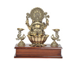 Front view of brass Lord Ganesha idol and two peacock oil lamps on wooden base