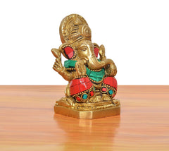 Brass Ganpati Bappa idol angled view; red, green and gold attire