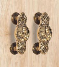 Golden brass door handle pair, curved backplates and two-god & goddess relief medallions