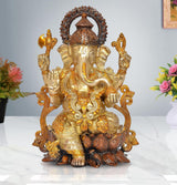 Brass Ganesha idol sitting on lotus with ornate halo, gold and dark accents
