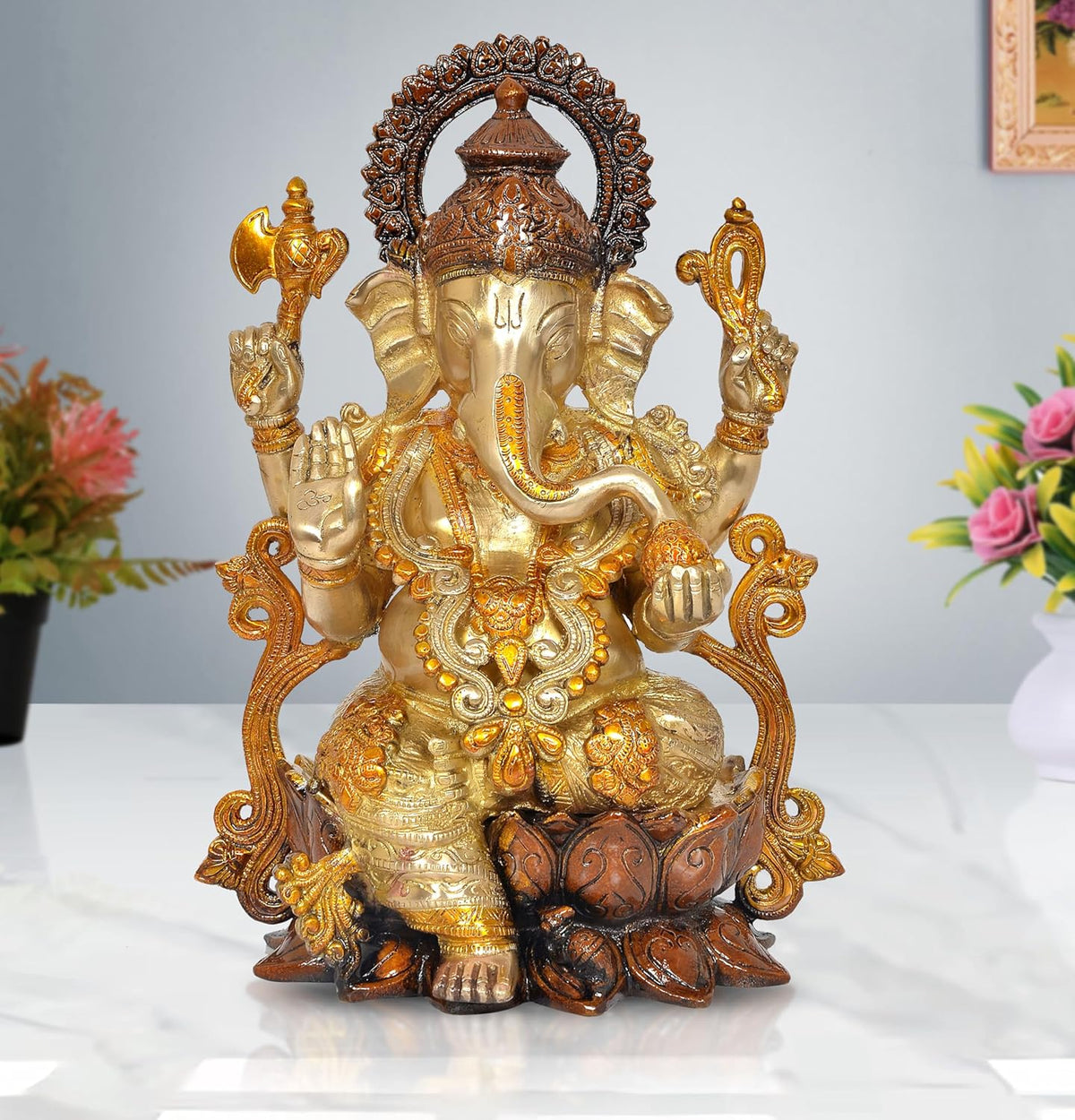 Brass Ganesha idol sitting on lotus with ornate halo, gold and dark accents