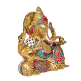 Seated brass Ganesha side view, colorful stonework on crown, arms, and attire
