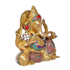 Seated brass Ganesha side view, colorful stonework on crown, arms, and attire