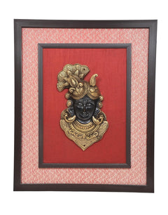 Close view of Shreenath ji brass face idol in inner black frame on red background