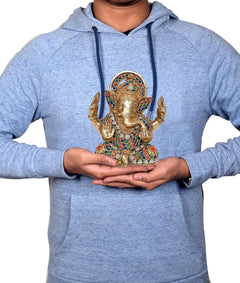 Brass Ganesh idol held in hands, colorful gem-inlay design for home pooja decor