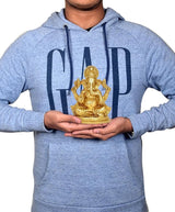 Brass Ganesha idol statue held in hands by a person, seated on a round base.