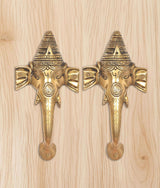 Brass Ganesha face door handle pair on light wood board, symmetrical front view