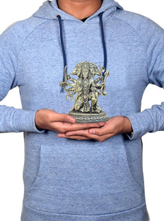 Brass Panchmukhi Hanuman idol held in hands on a blue hoodie chest