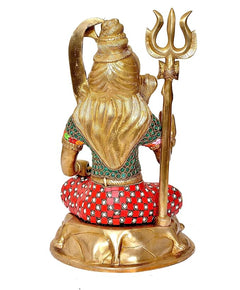 Rear view of brass Lord Shiva idol seated with trident, patterned red robe.