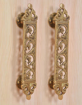 Golden brass door handle pair with ornate scroll filigree panels and round mounts