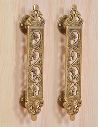 Golden brass door handle pair with ornate scroll filigree panels and round mounts