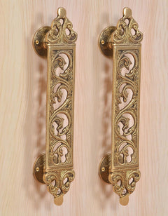 Golden brass door handle pair with ornate scroll filigree panels and round mounts