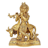 Gold-tone Krishna statue playing flute with cow figurines, detailed jewelry, square base