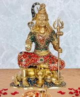 Brass Shiva murti sculpture, seated deity with trident and red-green jeweled attire