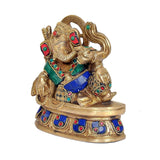 Brass Ganesha statue eating ladoo, seated with blue-and-green jeweled ornaments
