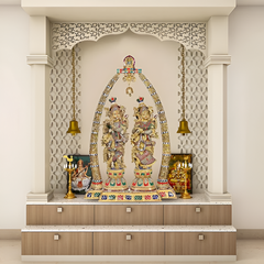 Brass Radha-Krishna statue beneath decorative arch with hanging bells and base