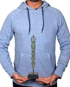 Person holding the vintage bronze phurpa ritual dagger on a dark display base