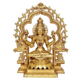 Gold Lakshmi idol seated in lotus pose, raised arms, detailed halo arch