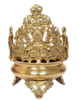 Brass urli bowl with central deity figurine, sculpted frame, and decorative pedestal