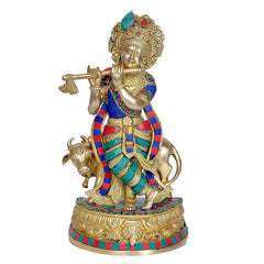 Brass Krishna idol with cow, blue red green patterned attire, playing flute