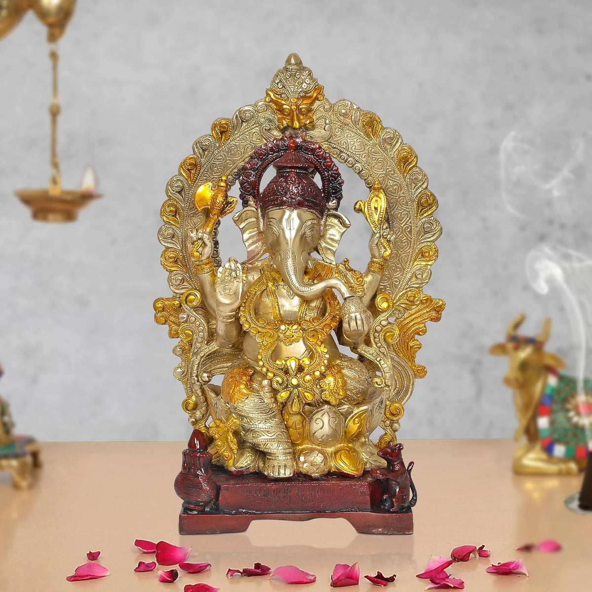 Brass Ganpati Bappa idol with ornate gold-toned arch, dark crown, on red base