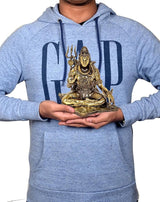 Hand holding gold-tone Lord Shiva brass sculpture, seated on base, 6 inch