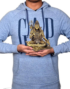 Hand holding gold-tone Lord Shiva brass sculpture, seated on base, 6 inch