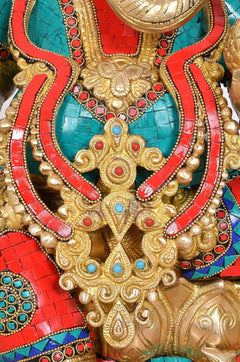 Close-up of Ganesha chest ornament: gold filigree over teal and red mosaic detailing