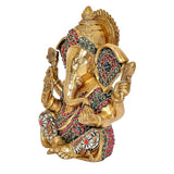 Golden Ganesha idol statue from side view, jeweled belt and raised hands