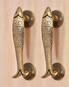 Brass fish door handle pair on light wood door, full length handle grips visible.
