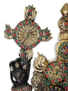 Close-up of brass idol arms and chest ornament with circular gem inlays and gold detailing