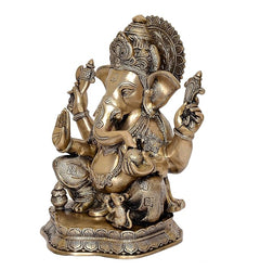 Brass Ganesha statue idol, side angle showing trunk curve, four arms and seated base