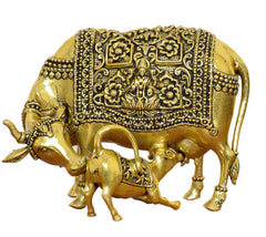 Golden brass cow figurine with calf, close-up ornate engraved patterns on body