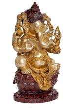 Angled view of seated Ganesha idol with detailed crown and dark red lotus pedestal