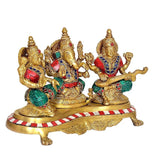 Brass Lakshmi Ganesh Saraswati statue, angled view with red/white striped base and gold details