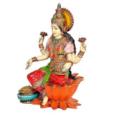 Lakshmi idol side view, red outfit with green sash, holding pot and round offering stand