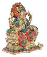 Sitting Ganesha idol angled view with red crown, teal-and-green ornaments, and raised hand